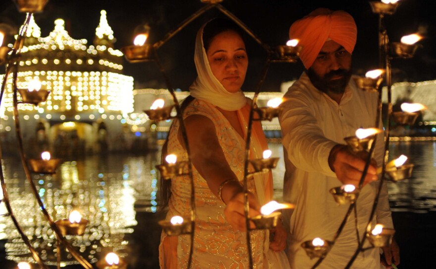 Sikh devotees Puneet Kaur (left) and Gurmeet Singh light lamps as they pay their respects at the Golden Temple in October. Temple authorities are considering installing solar panels for the lighting system to make it more environmentally friendly.