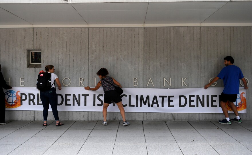 Activists unfurled a banner calling David Malpass a climate denier on the World Bank headquarters after he refused to say if he believed man-made emissions contributed to global warming.