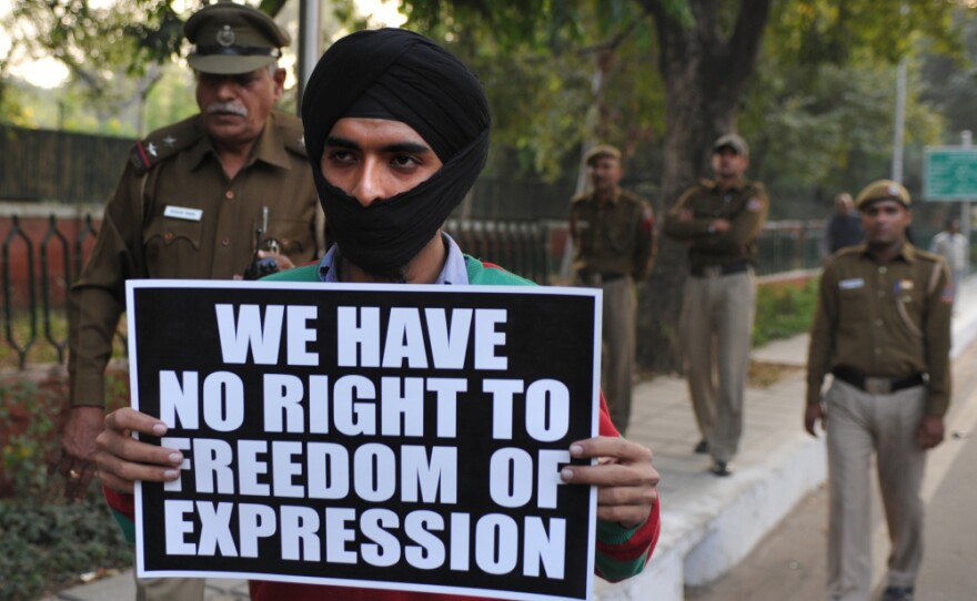 An activist of Bhagat Singh Kranti Sena hold placards and roses outside the residence of Communications and IT Minister Kapil Sibal in New Delhi.