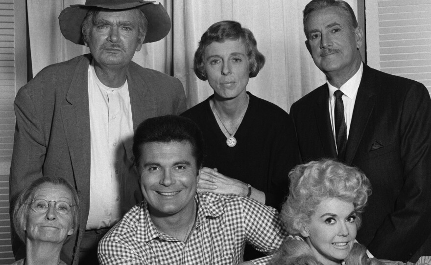 Donna Douglas as Elly May Clampett, lower right. Clockwise from upper left is Buddy Ebsen (as Jed Clampett), Nancy Kulp (as Jane Hathaway), Raymond Bailey (as Milburn Drysdale), Douglas, Max Baer, Jr. (as Jethro Bodine), and  Irene Ryan (as "Granny").