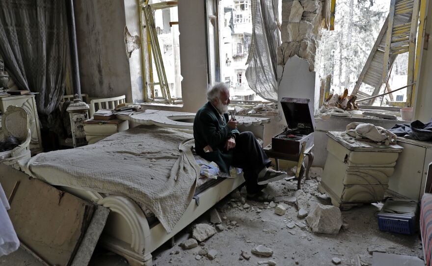 Mohammed Mohiedin Anis, known as Abu Omar, 70, sits amid the rubble in his bedroom while listening to music on his gramophone in the formerly rebel-held al-Shaar neighborhood of Aleppo, Syria.