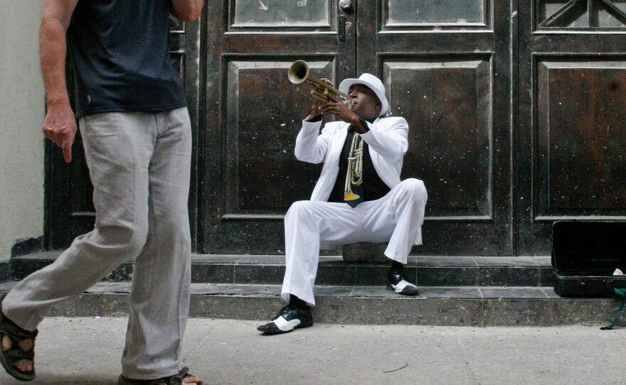 Tourists mill past a trumpet player in the restored part of Old Havana.