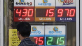 n this Oct. 18, 2018, file photo, a man walks past a lottery display outside of The Lucky Spot in San Francisco. 