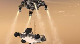 An artist's rendering shows a rocket-powered descent stage lowering the one-ton Curiosity rover to the Mars surface.