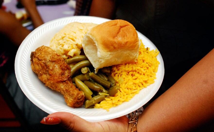 Soul food on a plate including fried chicken, green beans and macaroni & cheese.