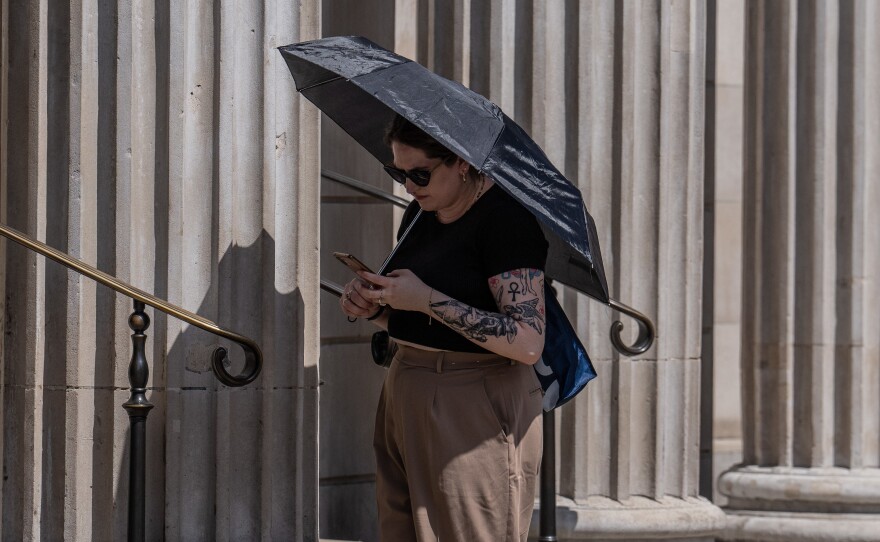 A woman shelters from the sun under a dark umbrella in London on Monday. Temperatures are forecast to hit well over 100 degrees in parts of the U.K. on Monday and Tuesday.