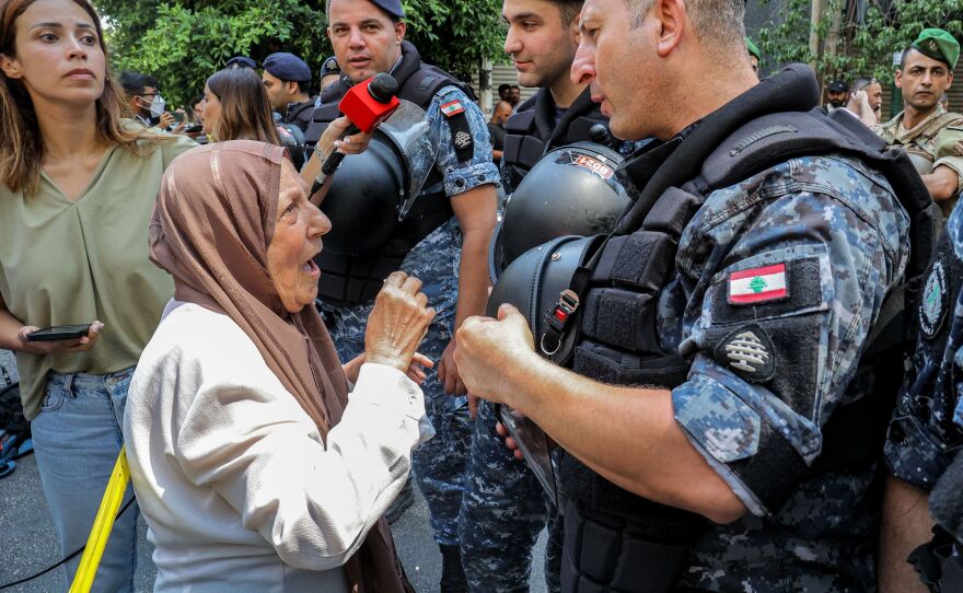 An angry bank client speaks with security forces outside the bank in Beirut on Thursday.