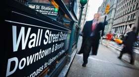 Office workers walk past the entrance to Wall Street subway station in New York's financial district.