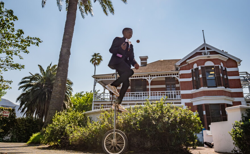 Aspiring magician Sibabalwe Sibaj, 17, juggles while riding a unicycle.