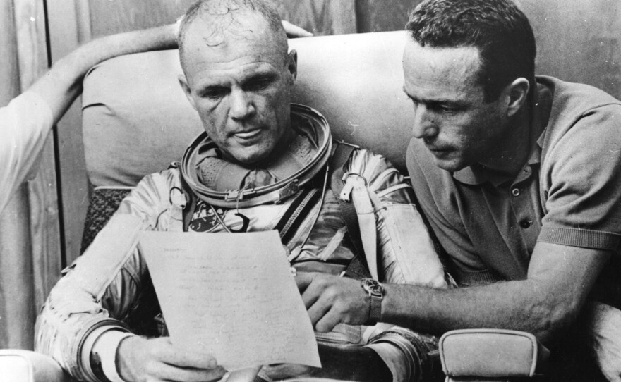 Glenn checks over notes with backup pilot Scott Carpenter after a simulated flight in 1962, prior to the Mercury-Atlas 6 mission at Cape Canaveral. The object of the mission was to put the first American spaceman into orbit around the Earth.