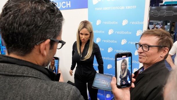 FILE - A Realbotix humanoid robot, center, speaks with attendees at a Realbotix booth during the CES tech show Jan. 8, 2025, in Las Vegas.