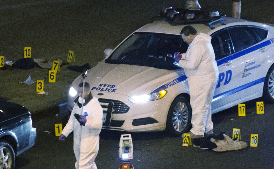 Investigators work at the scene where two NYPD officers were shot, on Saturday.