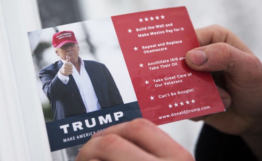 A volunteer for Republican presidential candidate Donald Trump leaves a card in a front door as he canvasses a neighborhood in New Hampshire.