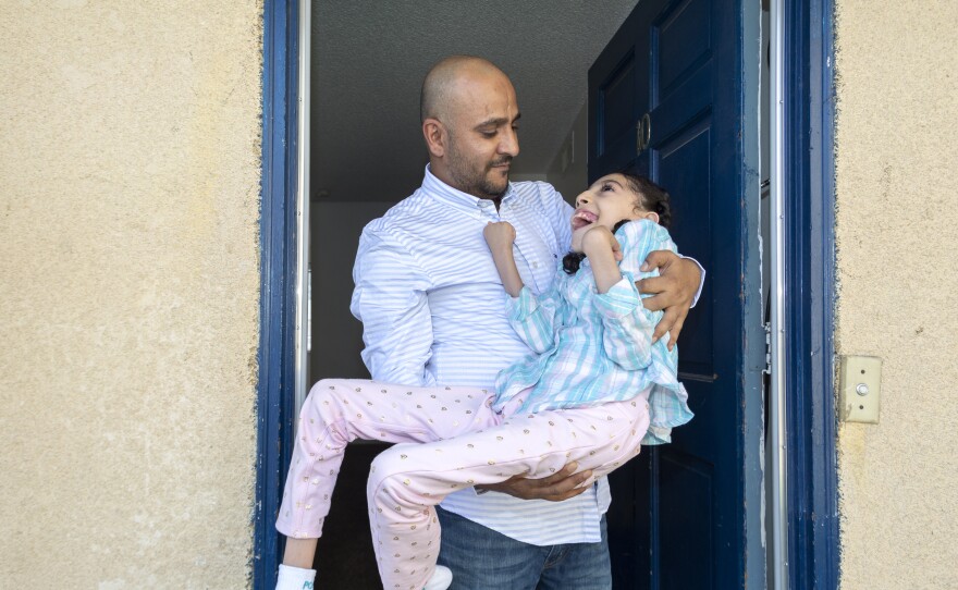 Nageeb Alomari holds his 10-year-old daughter, Shaema, in their front doorway just as he did outside the U.S. Embassy in Djibouti. Nageeb is from Yemen, but became an American citizen in 2010, and later applied for visas for his wife and daughters. Because Shaema is unable to walk on her own, Nageeb carried her to the family's appointment at the embassy.