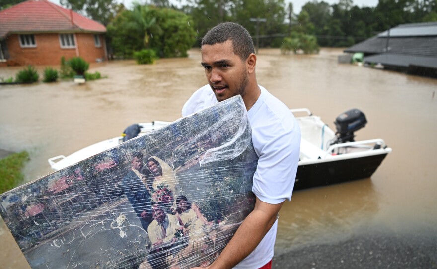 A man carries a wedding photo as people evacuate homes inundated by floodwaters Sunday in Goodna, Australia.