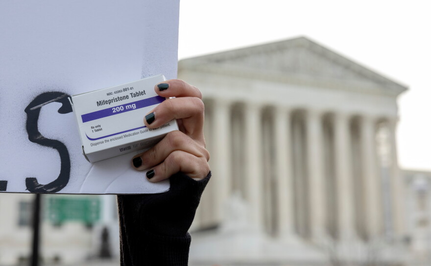 An abortion-rights activist holds a box of mifepristone pills as demonstrators from both anti-abortion and abortion-rights groups rally outside the Supreme Court on March 26, 2024.