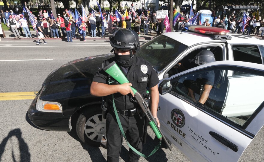 A police officer stands guard as supporters of President Donald Trump protest Wednesday in Los Angeles, Calif.