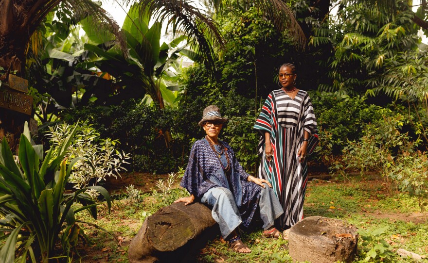 Farida Folawiyo (right) hosts the "Image Impressions" exhibition, with family portraits and collage and animated illustrations exploring migration. The venue is the private residence of Remi Vaugn-Richards (left), built by her father Alan Vaugn-Richards, a late British tropical-modernist architect. They're posing for a photograph in the Vaughan-Richards Garden.
