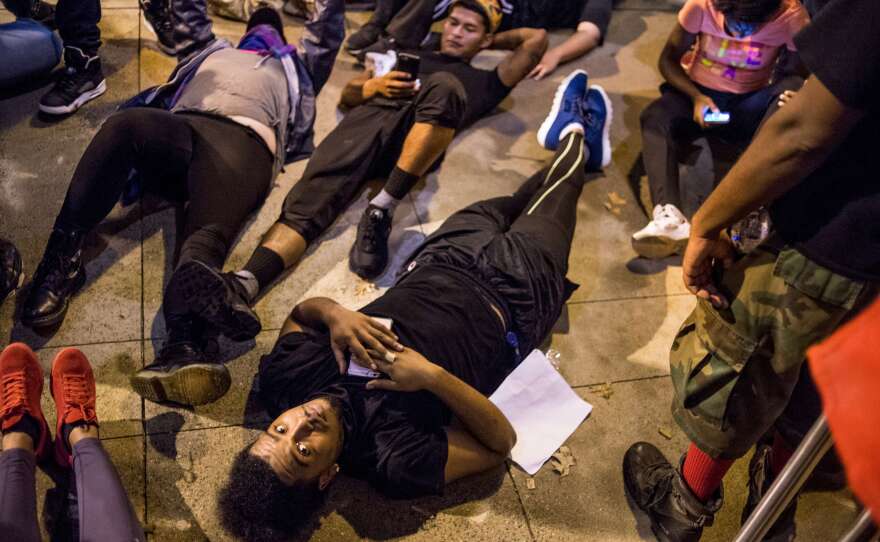 Demonstrators lie on the ground as they protest in front of the police station Thursday night in Charlotte, N.C. After two nights of violent unrest, protests on Thursday night were mostly peaceful, with no injuries or arrests reported.