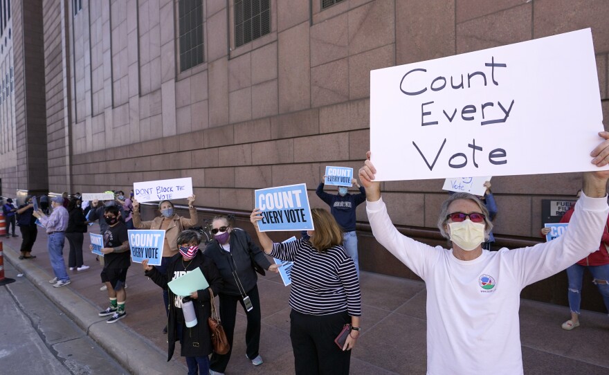 Demonstrators stand across the street from the federal courthouse in Houston, Monday, Nov. 2, 2020, before a hearing in federal court involving drive-thru ballots cast in Harris County.