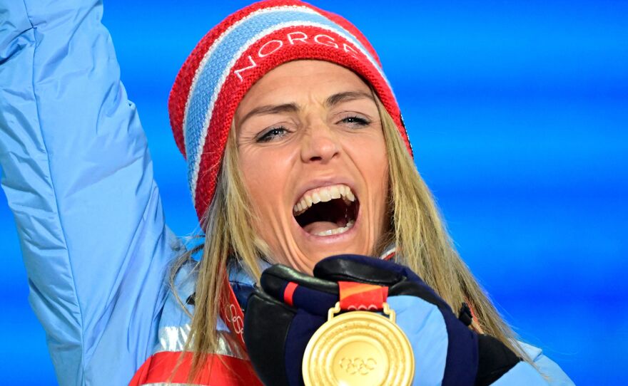 Medallist Norway's Therese Johaug, the first person to win gold at the Beijing Winter Olympics, celebrates on the podium during the women's skiathlon victory ceremony.