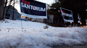 Polls show Rick Santorum and Mitt Romney in a tight race heading into Tuesday's Michigan primary. Santorum's campaign signs are stuck in the snow before his campaign stop at the The Colonial Valley Suites on Feb. 26 in Davison, Mich. 