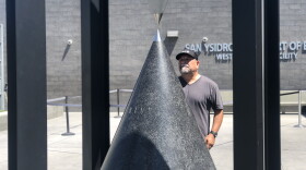 Tijuana artist Marcos Ramírez, who goes by "Erre," stands behind his new sculpture in front of the San Ysidro Port of Entry in this photo taken Sept. 5, 2019. 