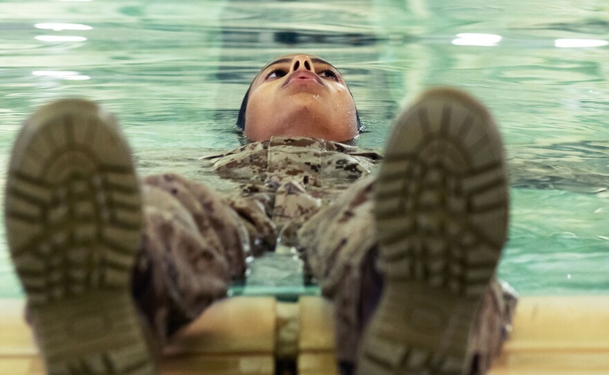 A female Marine recruit floats in a training pool during the water survival portion of boot camp, March 9, 2021.
