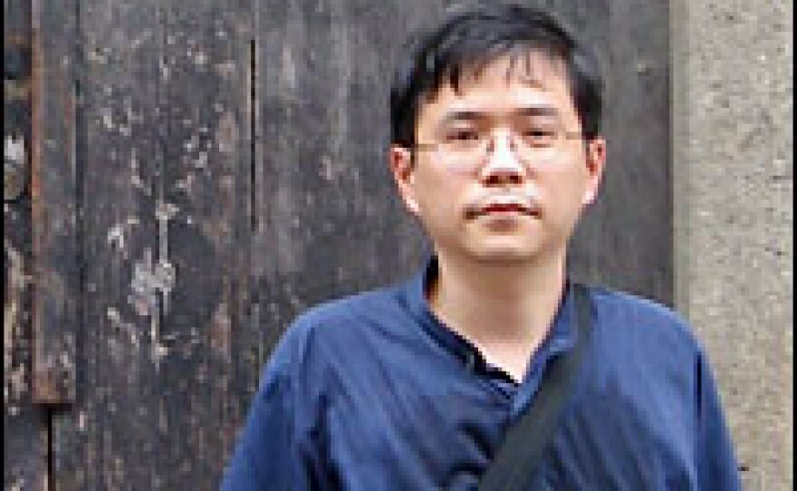 Shu stands outside the door of the house where he grew up.