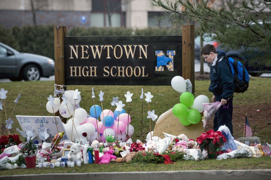 A student looks for a place to leave flowers at a makeshift memorial for the victims of the Sandy Hook Elementary School shooting at the entrance of Newtown High School on Tuesday in Newtown, Conn.