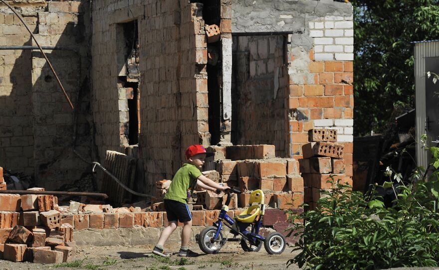 A boy plays in front of a destroyed house in the village of Andriivka, Kyiv region, on Friday, the 100th day of the Russian invasion of Ukraine.