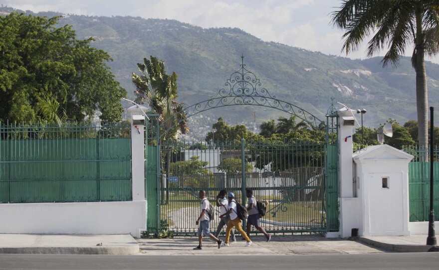 Pedestrians walk past the National Palace in Port-au-Prince, Haiti, Wednesday, July 7, 2021. A squad of gunmen assassinated Haitian President Jovenel Moise and wounded his wife in an overnight raid on their home Wednesday(AP Photo/Joseph Odelyn)