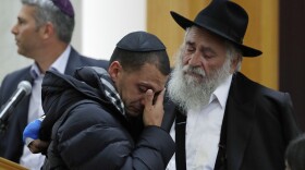 In this Monday, April 29, 2019, file photo, Rabbi Yisroel Goldstein, right, comforts Almog Peretz, center, as they attend the funeral for Lori Kaye, who was killed Saturday when a gunman opened fire inside the Chabad of Poway synagogue in Poway, Calif. 