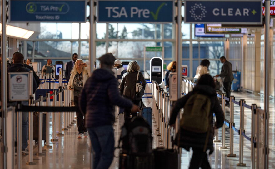 FILE - Travelers walk through a TSA security checkpoint at Reagan National Airport in Washington,  March 24, 2026.