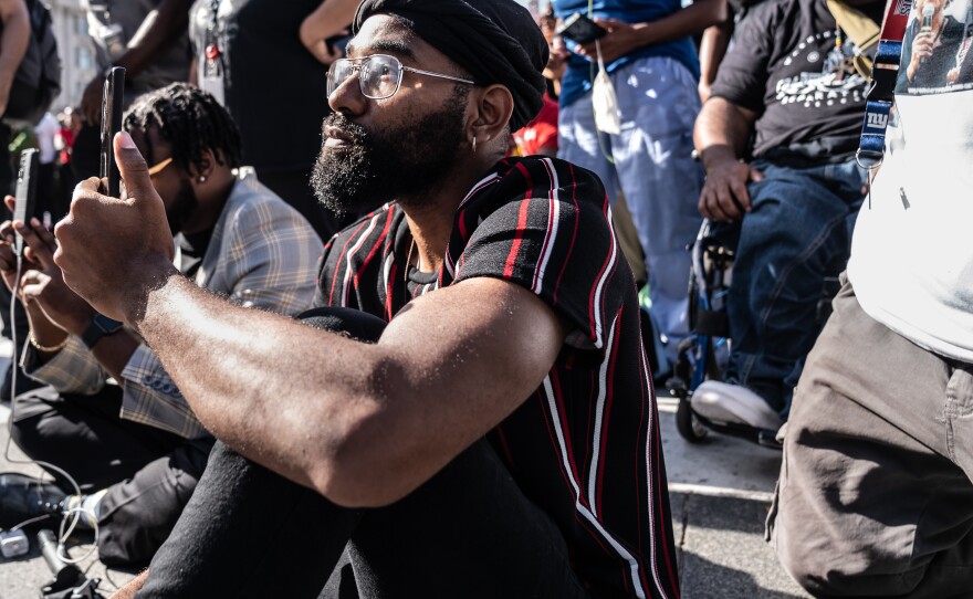 A Rally 4 Reparations attendee listens as host Tariq Nasheed speaks on the importance of reparations.