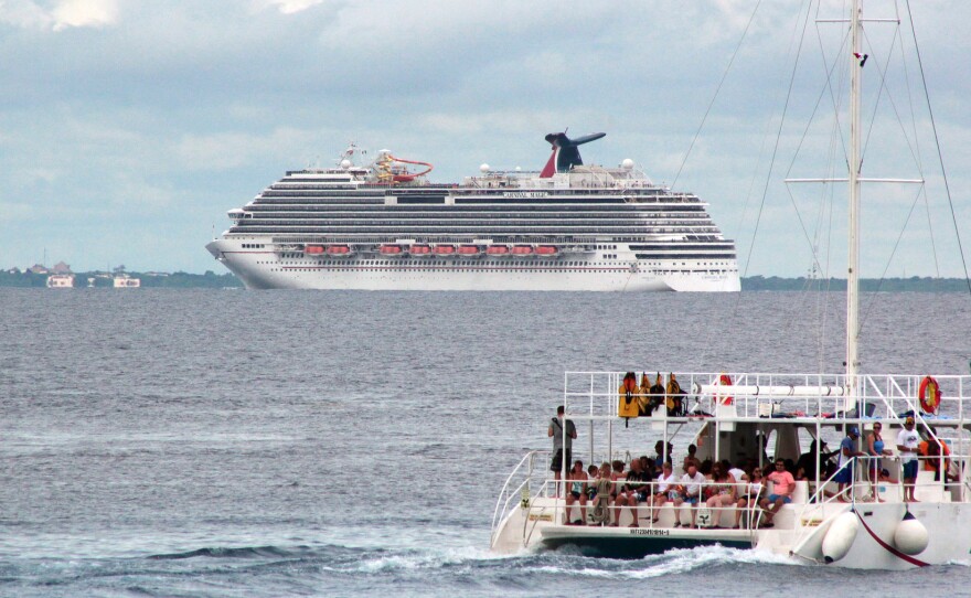 The cruise ship Carnival Magic floats behind a catamaran off Cozumel, Mexico on Oct. 17. The ship skipped a planned stop there Friday, the cruise line says, after Mexican authorities delayed granting permission to dock.