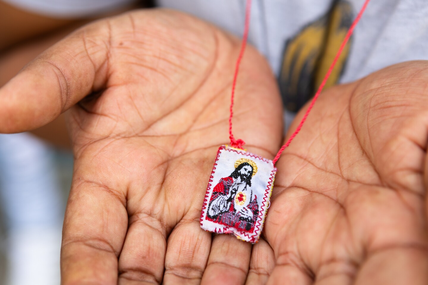 A woman who fled her home state of Mexico with her family holds a "detente," which she wears as a necklace for protection, Oct. 13, 2023.