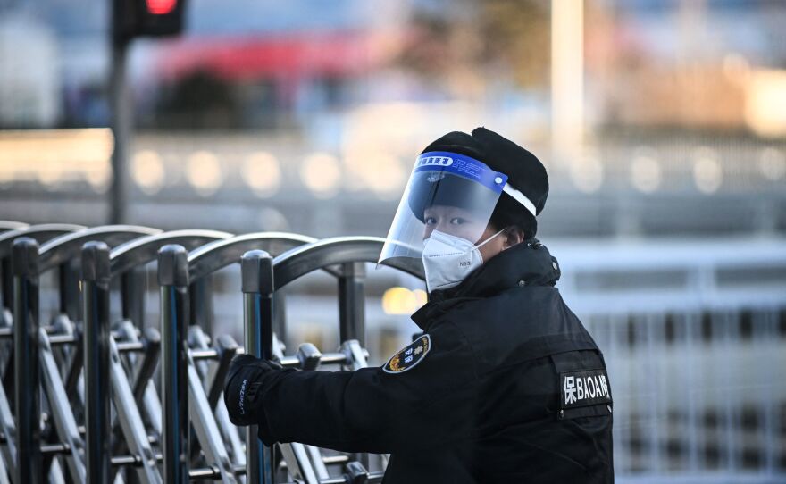 A security personnel opens a barrier at a checkpoint on a road within the closed-loop bubble in Beijing ahead of the 2022 Beijing Winter Olympic Games.