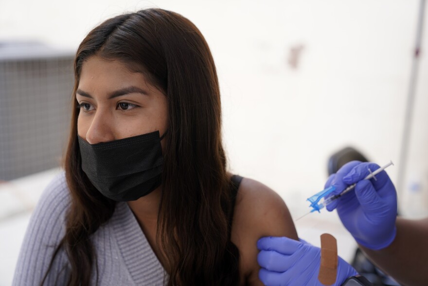 A young woman from Tijuana, Mexico, receives a vaccination shot against the coronavirus outside of the Mexican Consulate building, Thursday, Nov. 18, 2021, in San Diego. Scores of Mexican adolescents were bused to California on Thursday to get vaccinated against the coronavirus as efforts get underway across Mexico to get shots in the arms of teens.