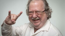Jim Allison smiles, displays Hook 'em Horns hand gesture.