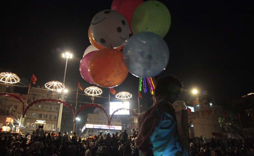 A child selling balloons amid worshippers and tourists sitting on boats facing the bank of the Ganges River in the holy Hindu city of Varanasi to watch the Ganga Aarti, a ritual of devotion to the venerated river.