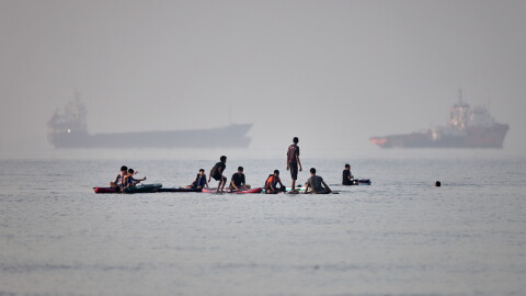 People gather on paddleboards in shallow water as cargo and service vessels are anchored in the Strait of Hormuz off Bandar Abbas, Iran, Monday, June 1, 2026.