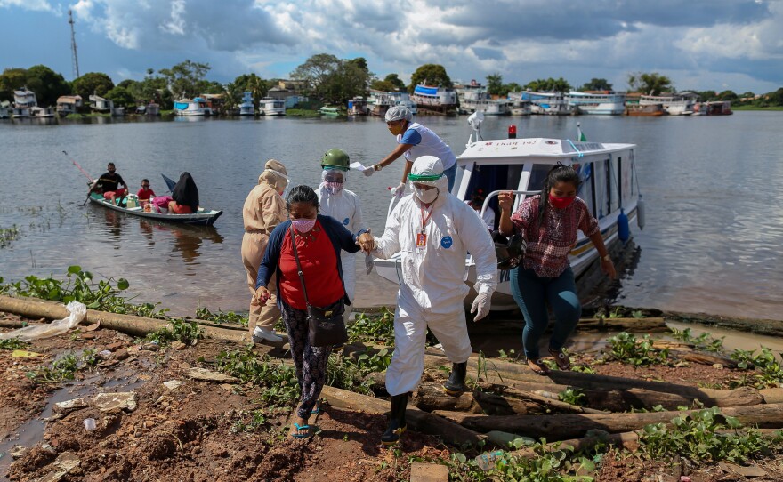 A surge in cases and record high daily death tolls have pushed Brazil into a COVID crisis. Above: Health professionals help patients with symptoms of the new coronavirus on a boat ambulance.