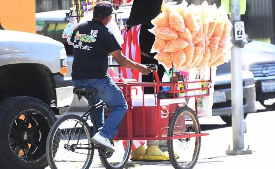 A street vendor works the busy intersection of Tulare and Cedar avenues, March 31, 2021. Local advocates are fanning out across Fresno to do outreach to street vendors, offering them pepper spray and other forms of protection.