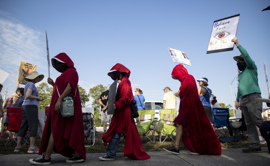 People dressed as characters from author Margaret Atwood's "The Handmaiden's Tale," were among the thousands who came to U.S. 41 and Daniels Parkway in Fort Myers Saturday for the third No Kings protest rally. Similar events were held in various Southwest Florida sites, other parts of the state and across the United States and the world.