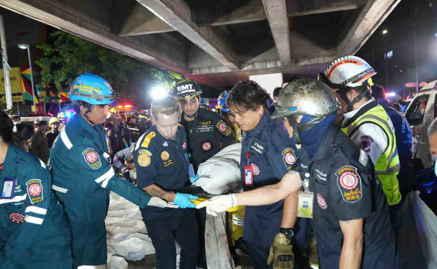 Rescuers carry the body of a victim of a fire in Bangkok, Thailand, Monday, July 13, 2026.