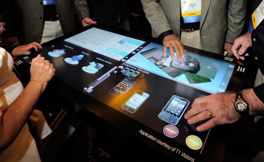 Attendees try a prototype 3M Touch Systems projected capacitive display at the Consumer Electronics Show in Las Vegas. Analysts say the way we interact with computers and other devices will be radically different in a few decades.