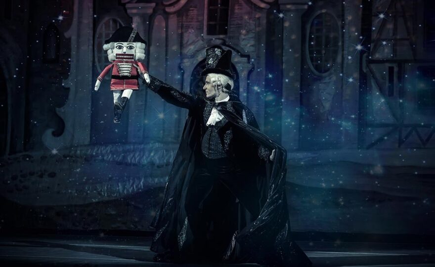 A dancer from the Grand Kyiv Ballet is shown in an undated performance photo of "The Nutcracker." He is dressed in a black cape and hat, and is holding up a nutcracker toy.