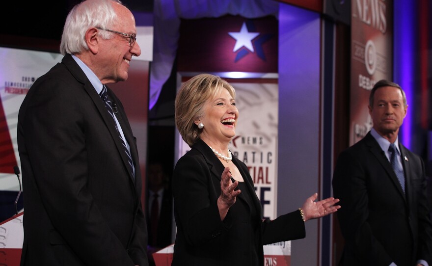 Democratic presidential candidates Bernie Sanders, Hillary Clinton and Martin O'Malley stand on the stage prior to Saturday's Democratic primary presidential debate in Des Moines, Iowa.