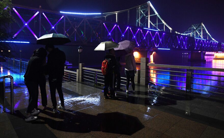 Visitors look at the China-North Korea Friendship Bridge across the Yalu River from Dandong, in northeast China. A company operating from Dandong is under fresh sanctions by the U.S.